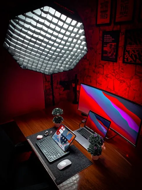 Un homme retouche l’image d’un fruit sur un MacBook Pro, assis dehors sur l’herbe.